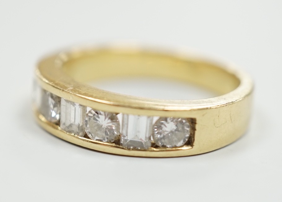 An 18k yellow metal, four stone round cut and three stone rectangular cut channel set diamond half hoop ring, size L, gross weight 4.9 grams.